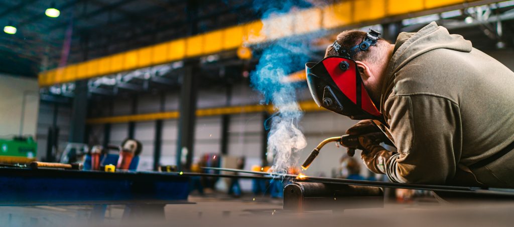 A welder is using different types of welding beads to join metal in a factory.